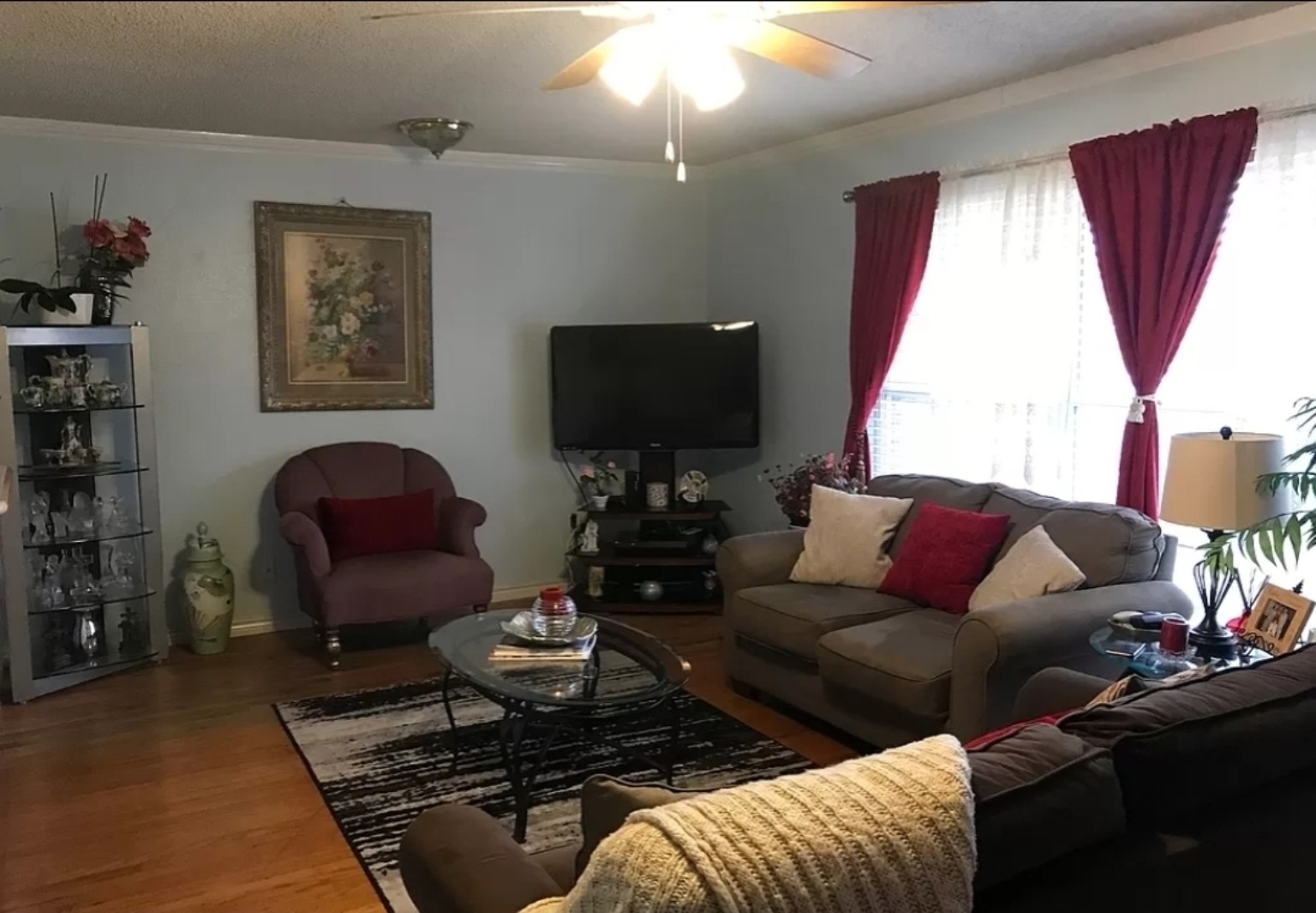 Before: a furnished living room with a ceiling fan, red curtains, sofas and a television in the corner.